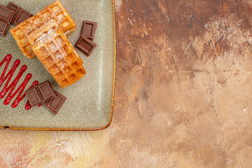 top view yummy waffle cakes with chocolate bars on brown background sweet dessert cake color biscuit free space