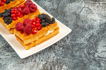 bottom view berry waffles on white rectangular plate on grey-white background with copy space