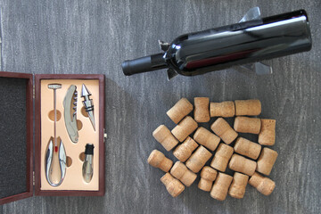 sommelier case with uncorking utensils, black bottle of red wine, crystal glass and corks