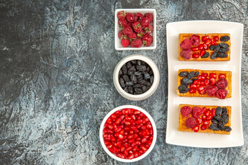 top view waffles with berries on white plate bowls with pomegranates raisins raspberries on...