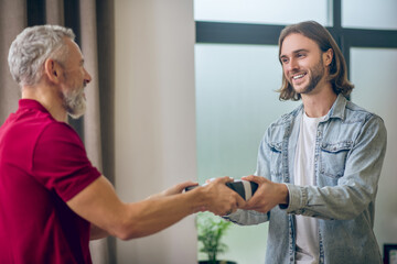 Young man in jeans shirt giving a present to his partner