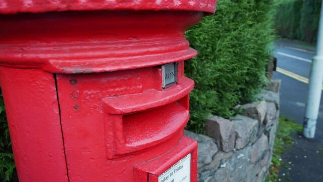 Letters are posted into a red royal mail letter post box in England.