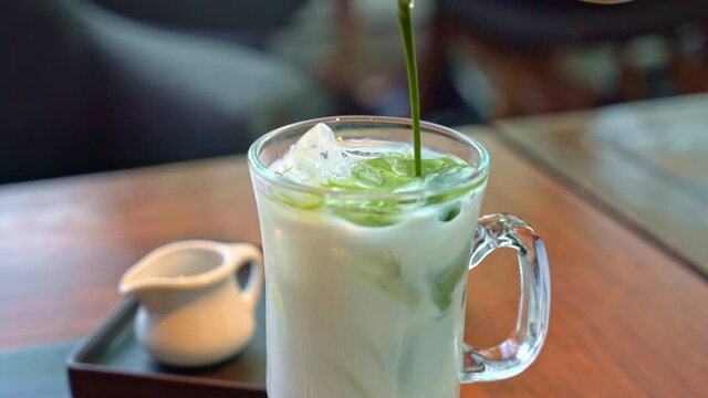 pouring matcha green tea in milk glass