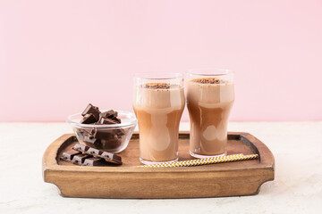 Wooden tray with glasses of tasty chocolate milk on table