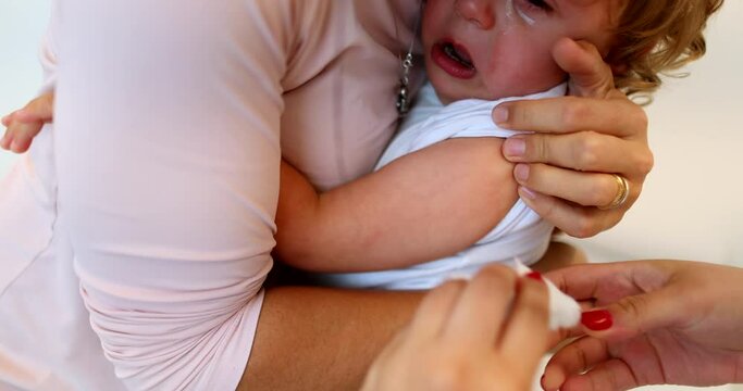 Medical procedure preparing to vaccinate baby child. mother holding infant for vaccination