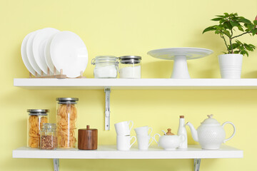 Utensils and glass jars with products on kitchen shelves