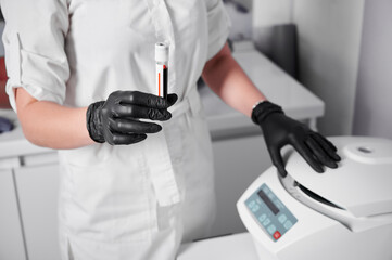 Plasmolifting process. Preparation of blood for injections. Cosmetologist in black rubber gloves...