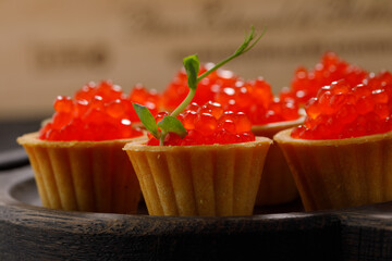 Appetizing tartlets with red caviar on a decorative board for serving. Holiday concept. Close-up.