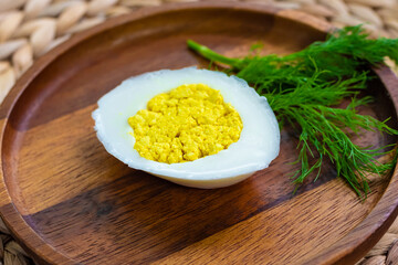 side view, vegetarian and vegan egg, milk and agar agar, tofu yolk and black salt with turmeric, egg on a wooden plate and garnished with a bunch of dill