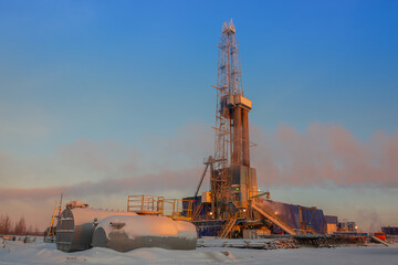 View of a drilling rig for drilling oil and gas wells in the rays of the rising sun. Winter polar...