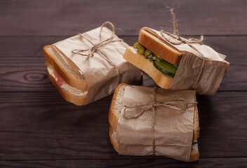 Fresh toast with salmon, cream cheese and vegetables lie in a pile, wrapped in craft paper. Healthy food concept.