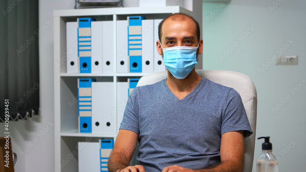 Poster man with mask working at computer and looking at camera sitting in office during pandemic. entrepren