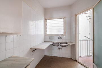 Fototapeta na wymiar Bright empty kitchen with small balcony, tiled floor and walls before renovation
