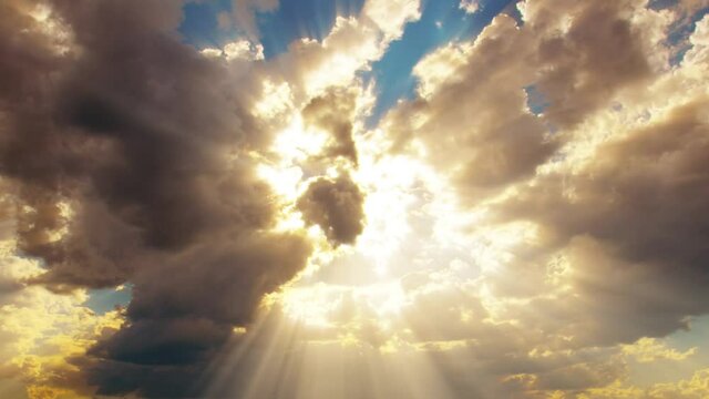 Sunlight through clouds. Timelapse of golden and bright sun rays shining down. Dark clouds moving away.