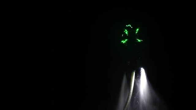 An unrecognizable flyboarder is making tricks at night. High quality 4k footage