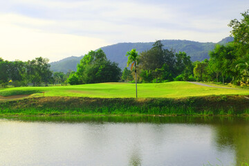 A pond with greenery trees and golf fairway on mountain and blue sky background 1