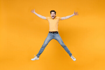 Fototapeta na wymiar Full length body young overjoyed caucasian excited fun happy surprised man 20s wearing casual t-shirt jeans high jumping up fooling around spread hands isolated on yellow background studio portrait