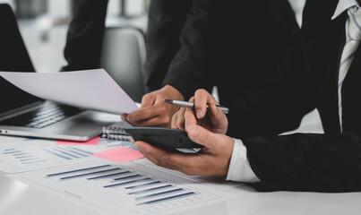 Businessmen use a calculator to calculate company financial statements for their colleagues, view and jointly solve problems within the company. Business finance and accounting concepts