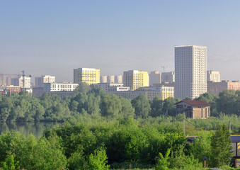 Obraz premium Tall houses among green trees