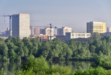 Obraz premium Tall houses among green trees