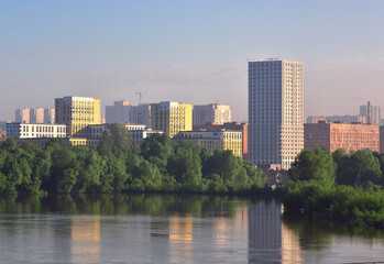 Naklejka premium Tall houses among green trees