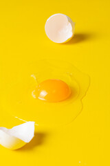 Cracked chicken egg with yolk and eggshell. Minimal Easter holiday concept Egg shell and egg yolk Creative copy space on a yellow background