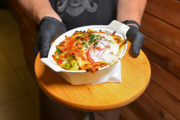 Italian lasagna in white pot. Waiter serving Italian lasagna in restaurant.