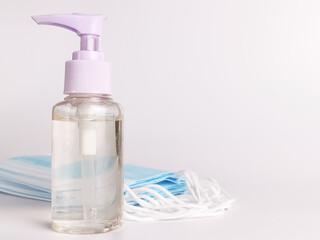 White background with a bottle of hand sanitizer and a bunch of disposal face mask. Selective focus.Medical concept.