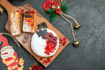 top close view tart and waffles with berries on wood cutting board around different xmas pendants on dark background with copy space