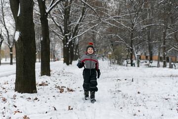 Fototapeta na wymiar Boy walks in snow-covered winter park. Walking with children in winter