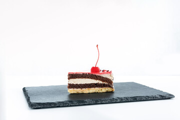 Piece of layered cake with maraschino cherry. Side view to piece of cake on white background