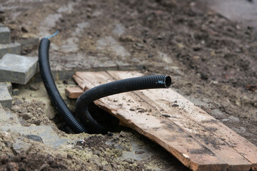 Thin diameter ribbed black PVC pipe in the ground before laying