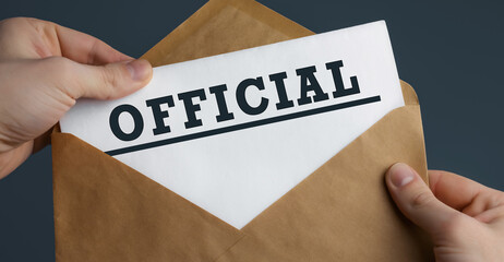 Male hands holding craft envelope with word OFFICIAL on blue background