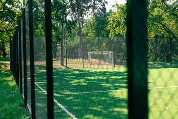 Soccer field behind the iron fence. School soccer stadium