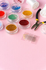 Items for creativity. Beads, fishing line and wire cutters on pink background, copyspace