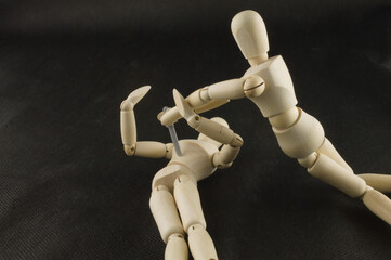 Mannequin holding a knife over another manikins chest isolated on a black background, Knife crime concept