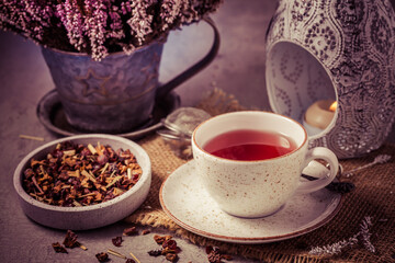 Obraz na płótnie Canvas Cup of fruit tea with dried tea leaves in vintage look