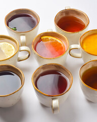 White tea, green tea, black tea, fruit and berry tea in ceramic cups. Many cups over white background.