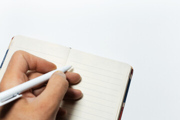 Close-up of male hand writing in notepad on white background.