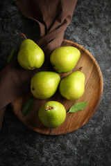 Wooden tray with green pears on black smokey background