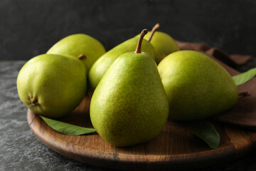 Wooden tray with green pears on black smokey background