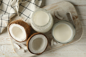 Board with fresh coconut and coconut milk on wooden background
