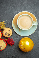 Vertical view of freshly baked delicious cupcakes with a cup of coffee and colorful decorations on dark background
