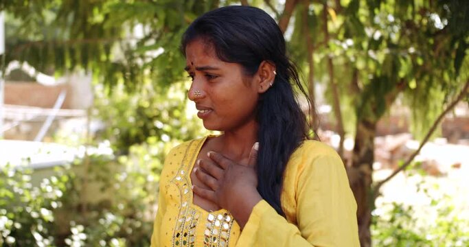 Slow-motion close-up portrait of a young adult Indian woman outdoors making expressions hand gestures signs- smells something stinking fowl as she holds her nose to stop breathing