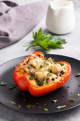 Stuffed sweet peppers with rice mushrooms and cheese with herbs. Baked halves of red pepper with filling. Grey concrete background. Copy space,
