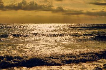 Obraz premium Beach sunrise and orange sea in the warm summer sun. Sandy coast and calm. High quality photo Sea waves on the sunset beach. Warm orange sea and sand. Restless ocean in the sun.
