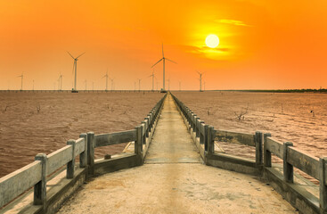 Fototapeta na wymiar Clean energy, wind power plant in sunset sky with a pathway to the giant wind turbines at sea to provide electricity for human life.