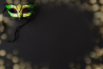 Mardi gras background on black with mask, golden bokeh and copy space