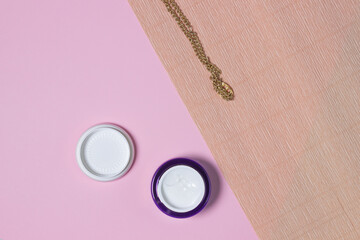 Cosmetics on a pink background. Cream in a round jar on a geometric background. Photo in pastel shades. Pastel aesthetics in photography.
