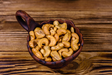 Ceramic bowl with roasted cashew nuts on a wooden table